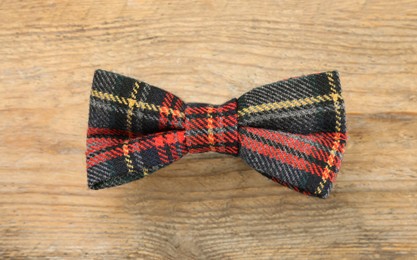 Photo of Stylish tartan bow tie on wooden background, top view