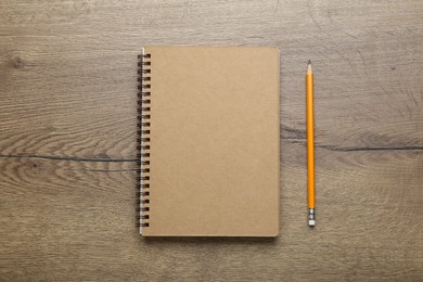Photo of Notebook and pencil on wooden table, top view