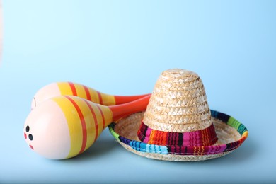 Colorful maracas and sombrero hat on light blue background. Musical instrument