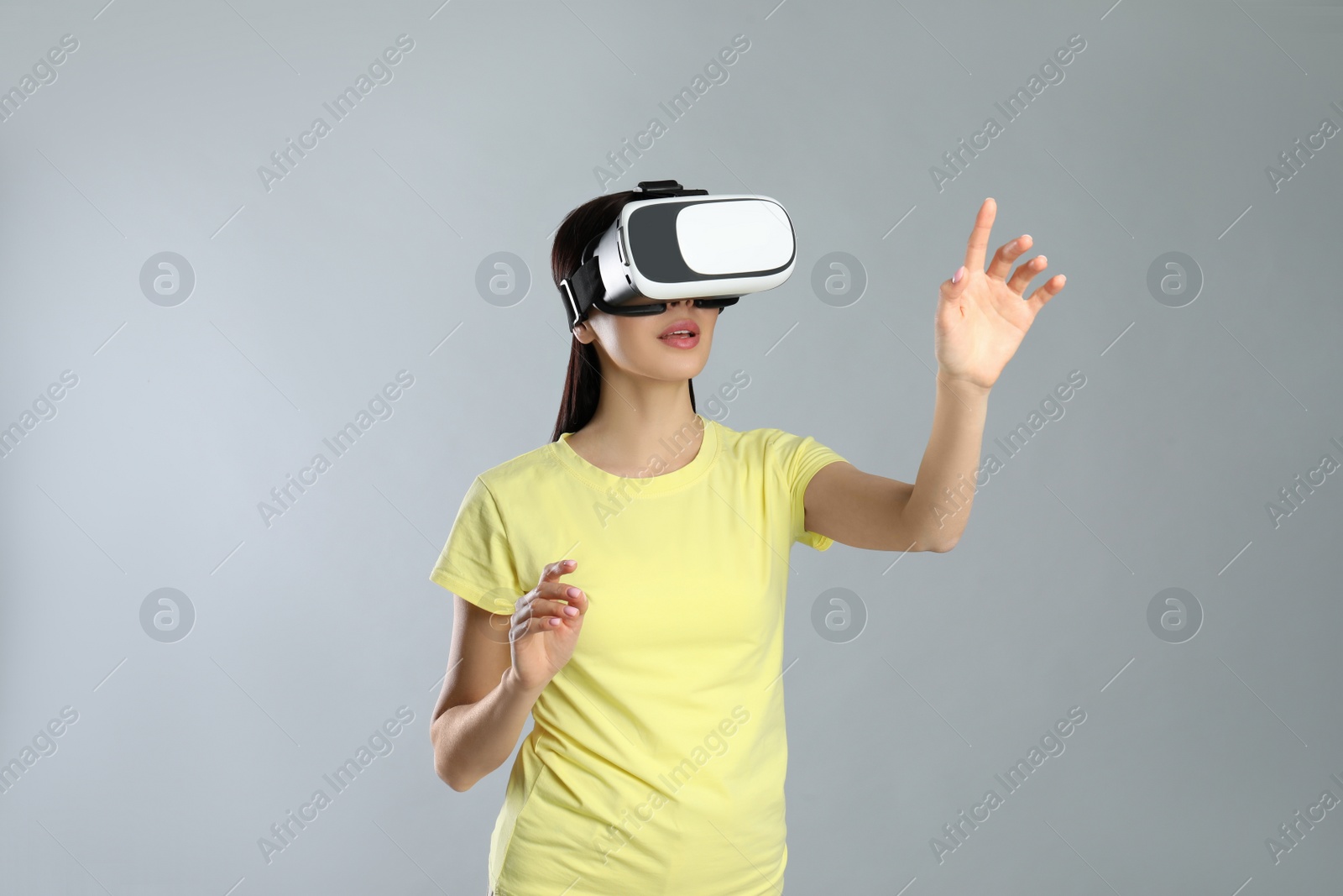 Photo of Woman using virtual reality headset on grey background