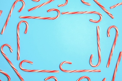 Photo of Flat lay composition with tasty candy canes and space for text on color background