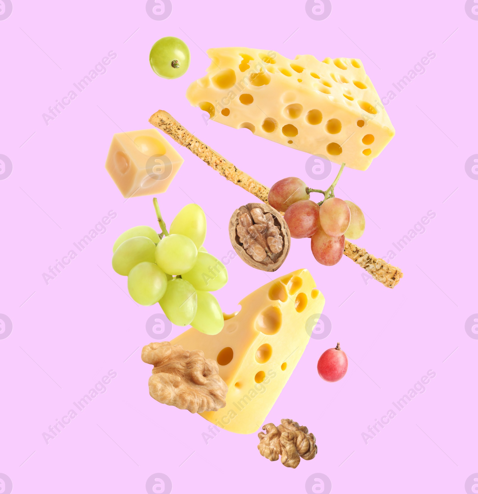 Image of Cheese, breadstick, grapes and walnuts falling against violet background