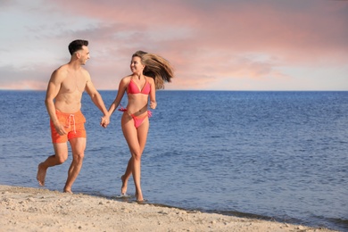 Photo of Young woman in bikini spending time with her boyfriend on beach. Lovely couple