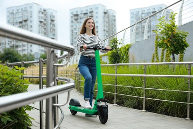 Photo of Happy woman with modern electric kick scooter on city street, space for text