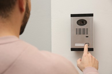 Photo of Man ringing intercom with camera in entryway