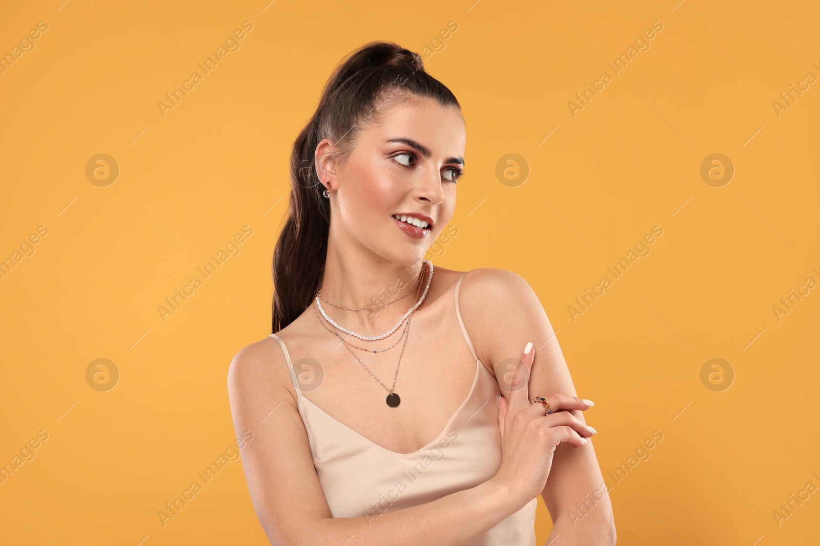 Photo of Beautiful woman with elegant jewelry on orange background