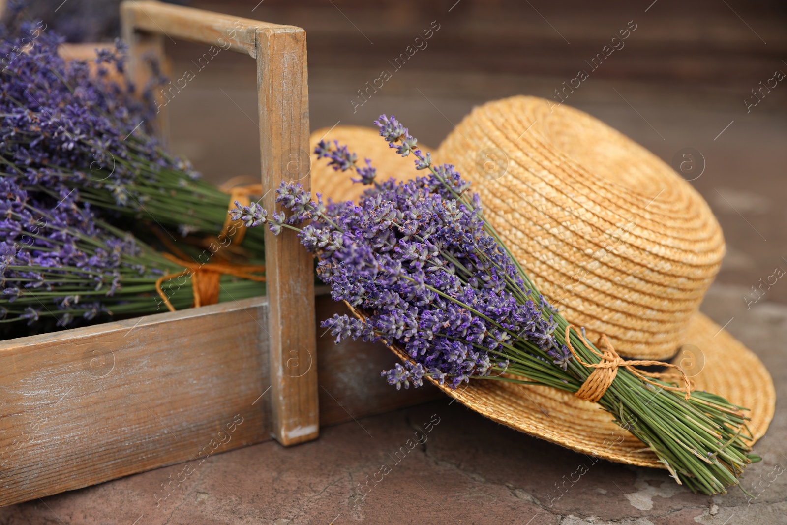 Photo of Beautiful lavender flowers and straw hat on cement floor outdoors