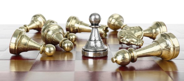Photo of Silver pawn among fallen golden chess pieces on wooden board against white background