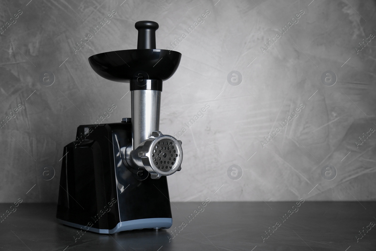 Photo of Modern electric meat grinder on black table. Space for text