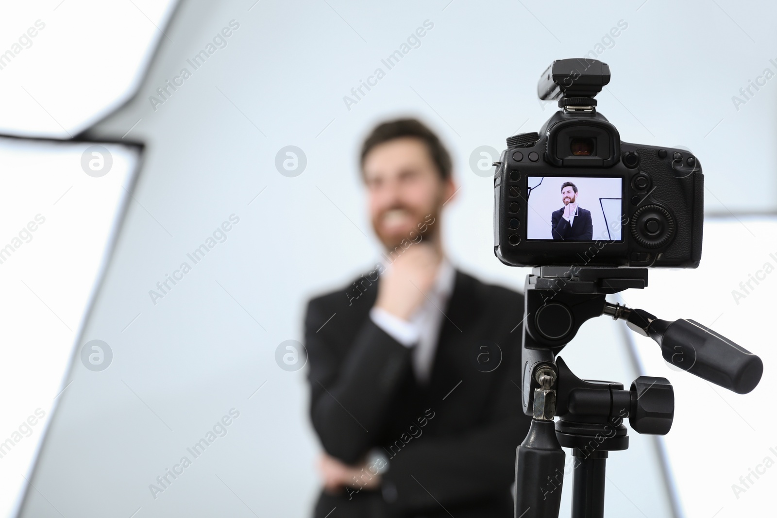 Photo of Handsome happy model posing for camera in modern studio, selective focus. Professional photo session