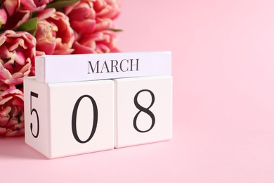 Photo of International Women's day - 8th of March. Block calendar and bouquet of beautiful tulips on pink background, closeup