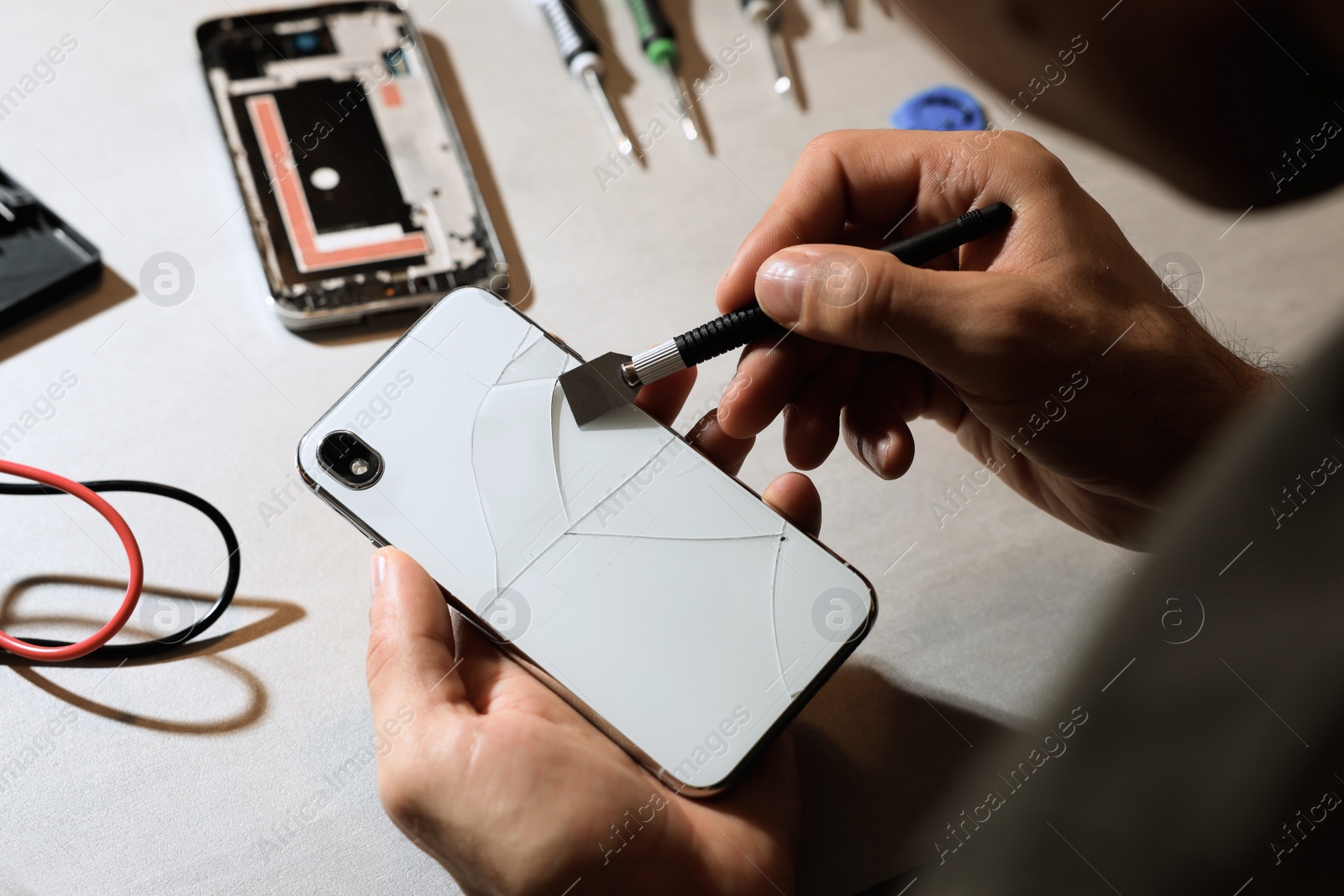 Photo of Technician repairing broken smartphone at table, closeup