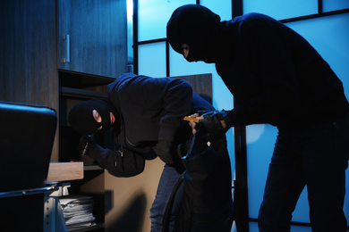 Photo of Thieves taking gold bars out of steel safe indoors at night