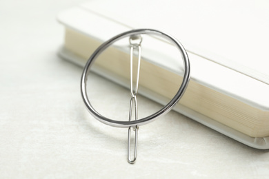 Beautiful hair clip and book on white table, closeup