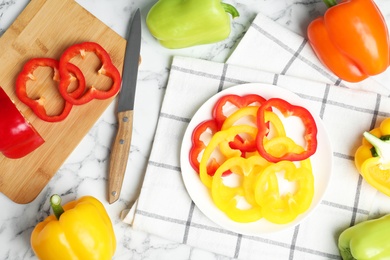 Flat lay composition with whole and cut ripe bell peppers on marble table