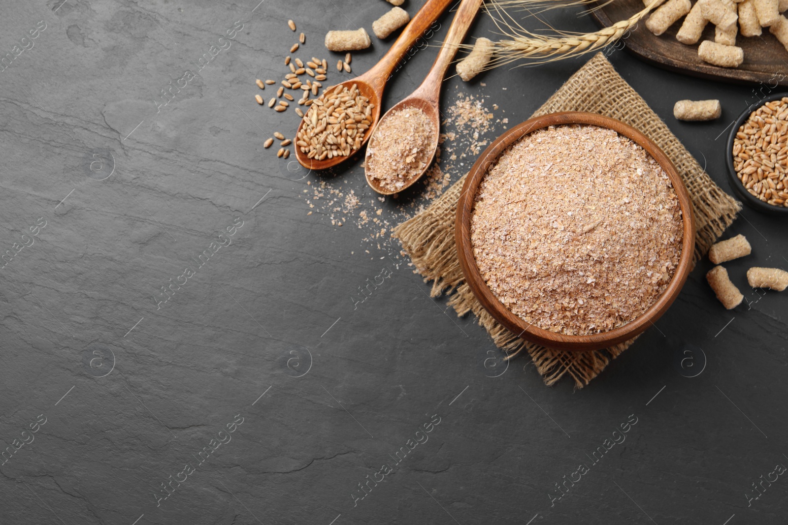 Photo of Wheat bran on black table, flat lay. Space for text