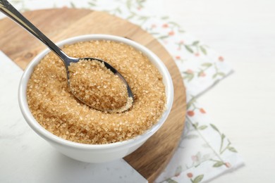 Photo of Brown sugar in bowl and spoon on table, closeup