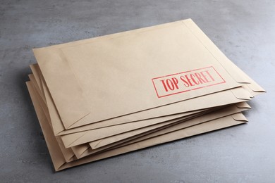 Image of Top Secret stamp. Stacked paper envelopes on grey table