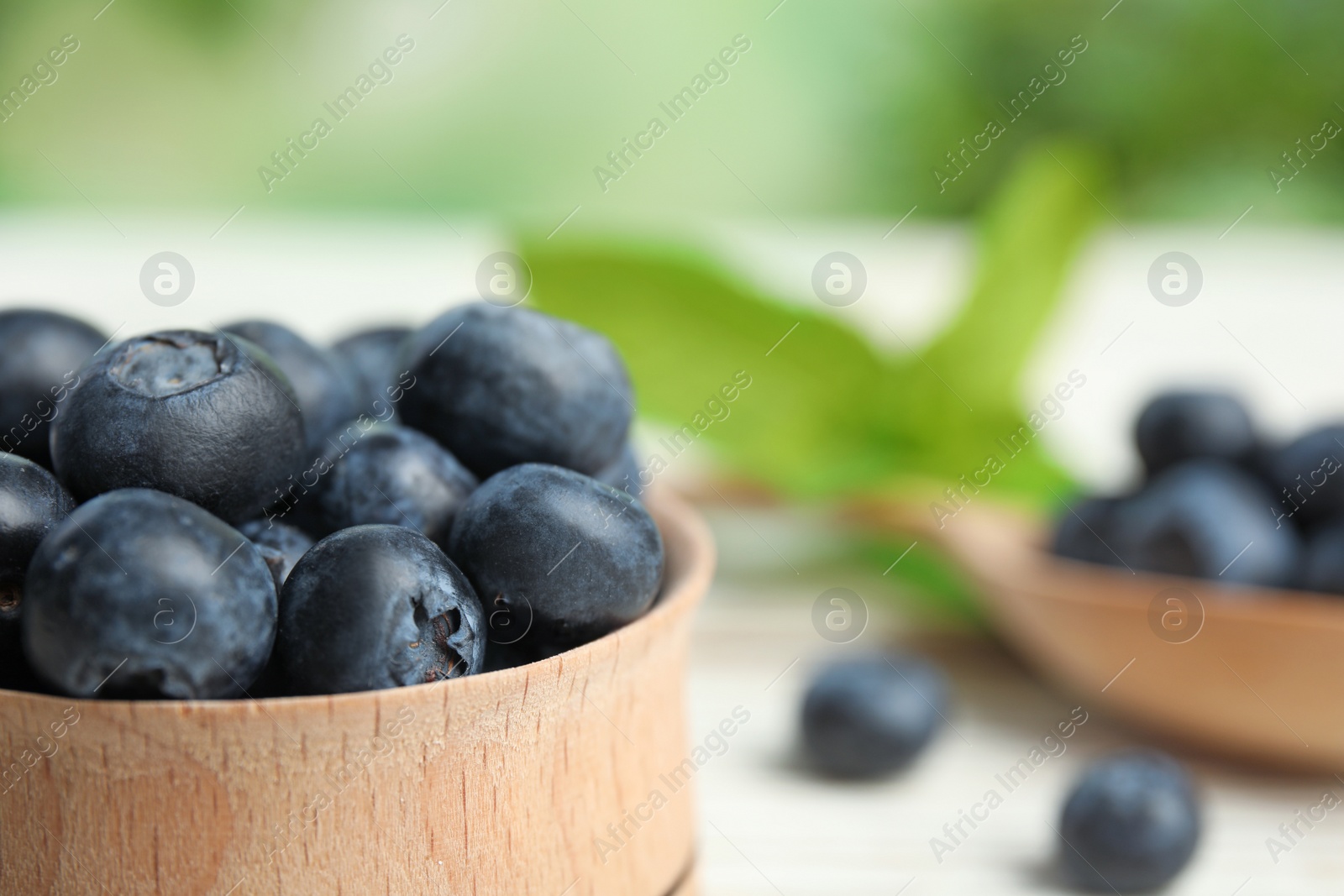 Photo of Wooden bowl with tasty blueberries on table, closeup. Space for text