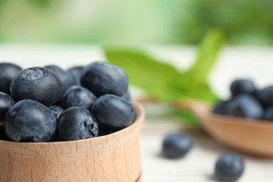 Wooden bowl with tasty blueberries on table, closeup. Space for text