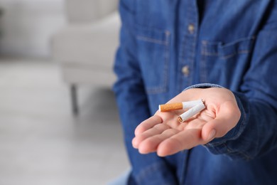 Quitting smoking concept. Woman holding broken cigarette on blurred background, closeup. Space for text