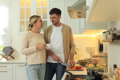 Photo of Happy couple spending time together while preparing food in kitchen