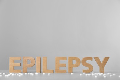 Photo of Word Epilepsy made of wooden letters and pills on grey table, space for text
