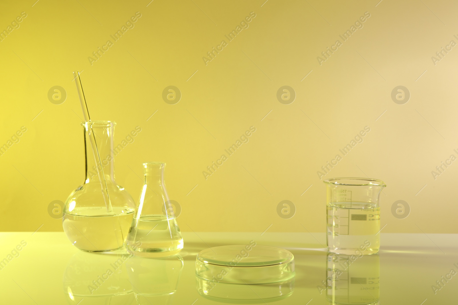 Photo of Laboratory analysis. Different glassware on table against yellow background