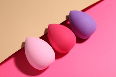 Photo of Many different makeup sponges on color background