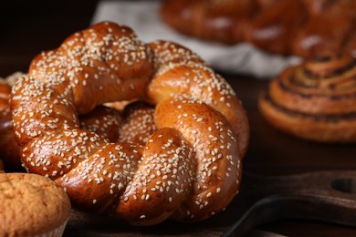Freshly baked round braided bread and other pastries on table, closeup
