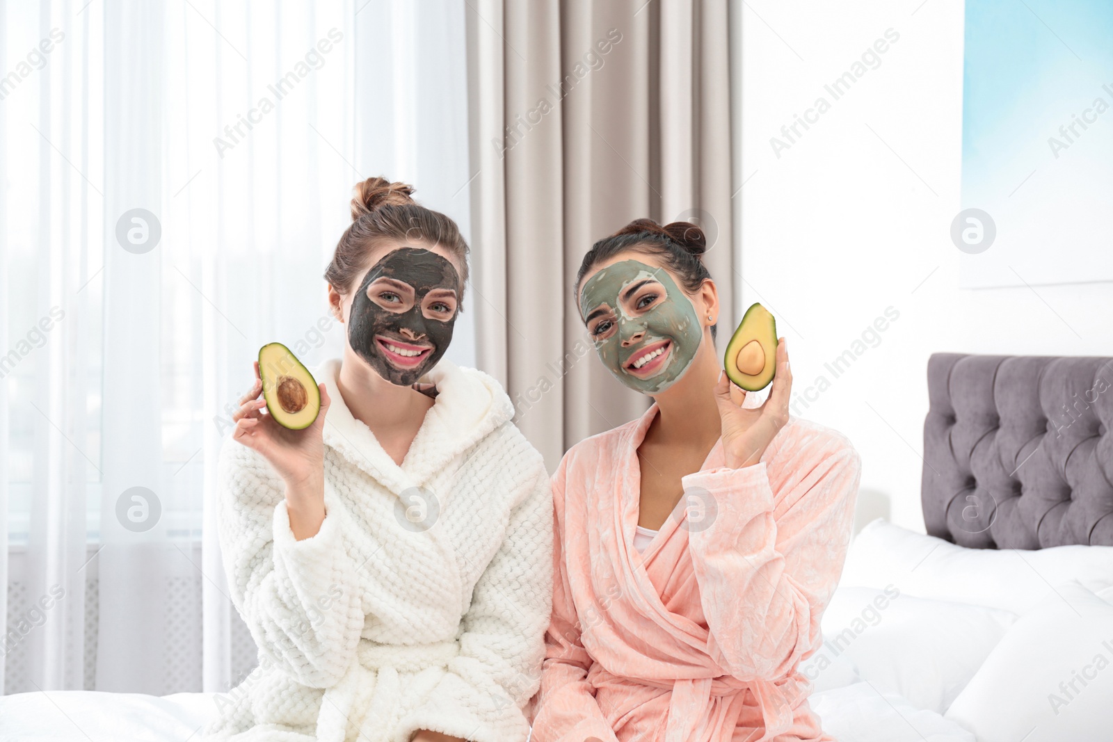 Photo of Young friends with facial masks having fun in bedroom at pamper party