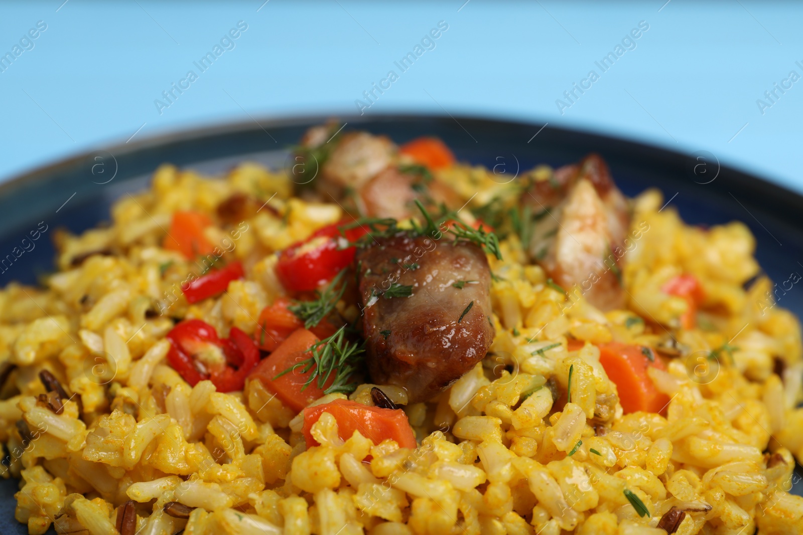 Photo of Delicious pilaf with meat, carrot and chili pepper on plate, closeup