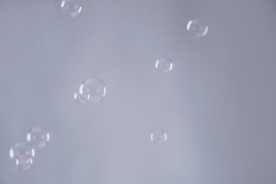 Beautiful translucent soap bubbles on grey background