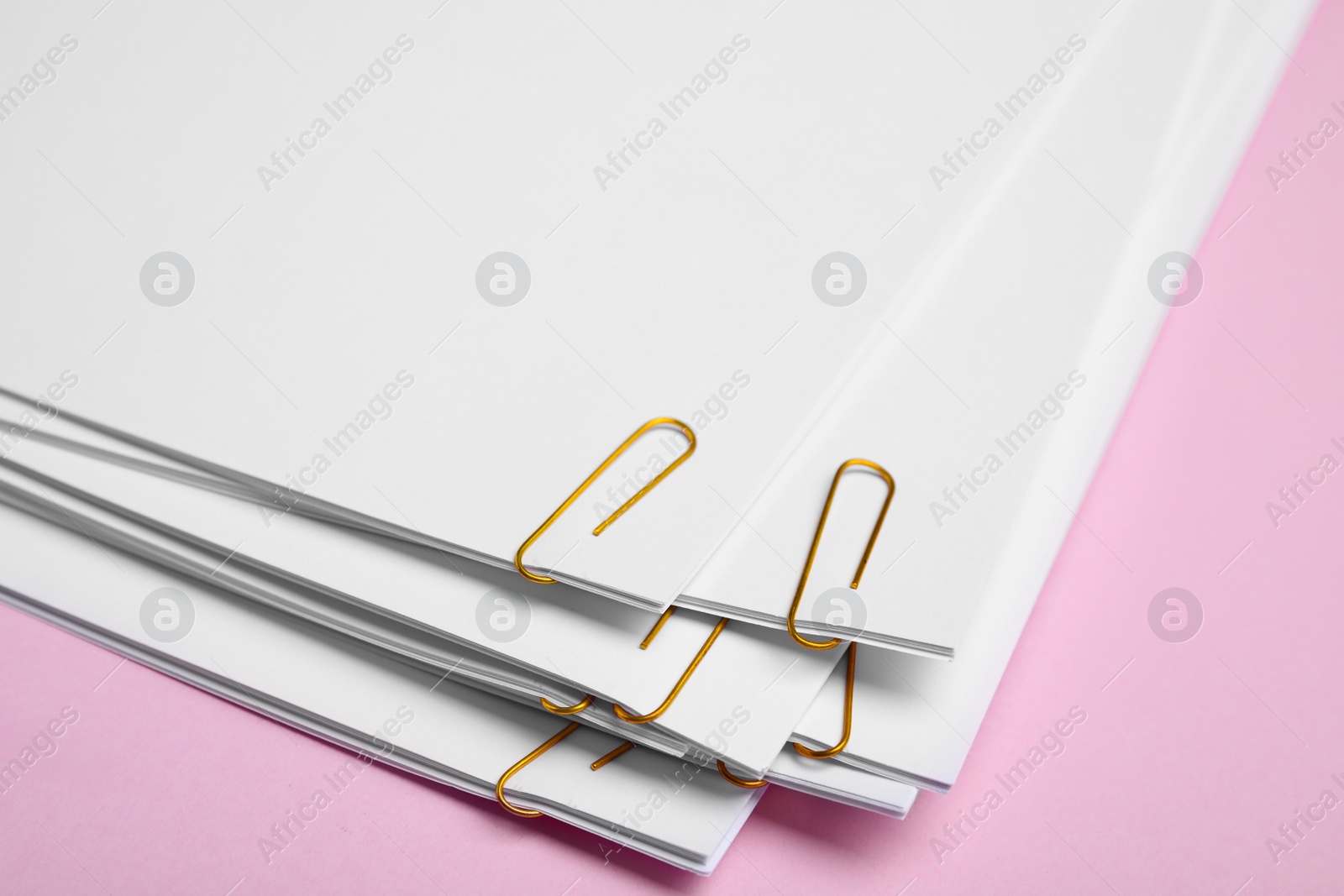 Photo of Sheets of paper with clips on pink background, closeup