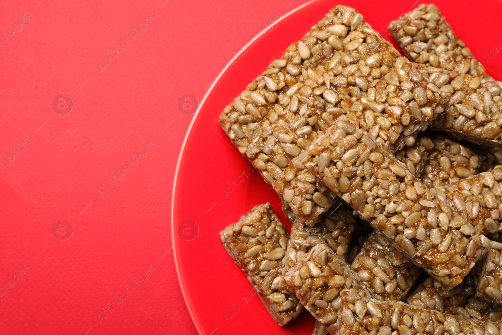 Photo of Delicious kozinaki bars on red background, top view. Space for text