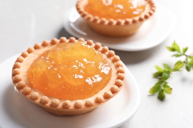 Tasty tartlets with jam on light background