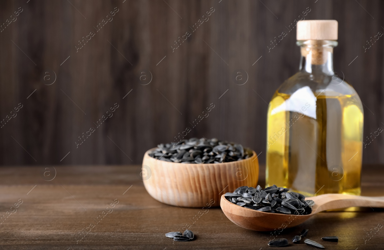 Photo of Sunflower seeds and oil on wooden table. Space for text
