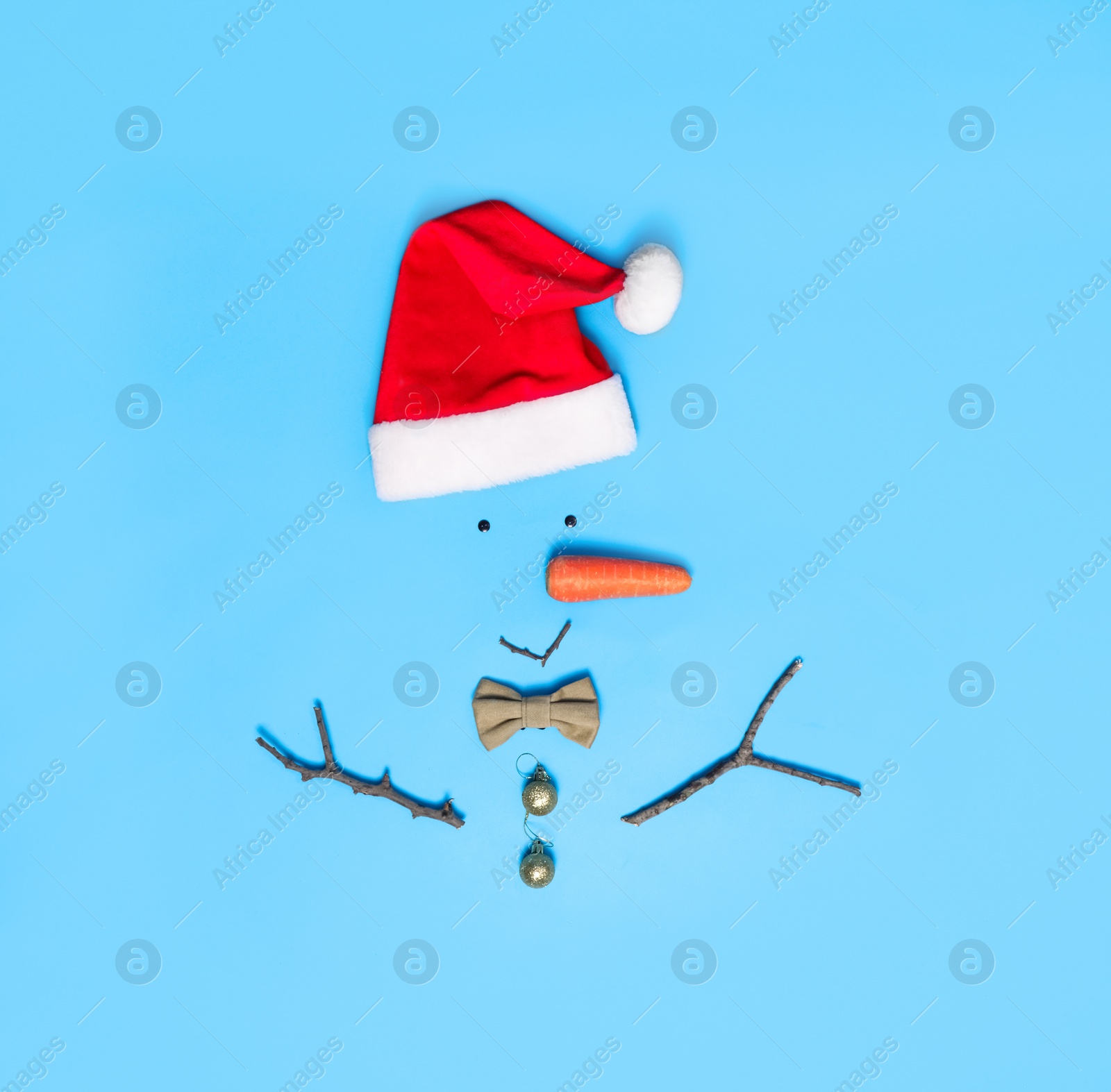 Photo of Creative snowman shape made of Santa hat and different items on light blue background, flat lay