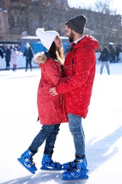 Lovely couple spending time together at outdoor ice skating rink