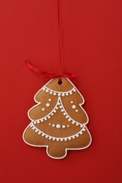 Photo of Christmas tree shaped cookie on red background, top view