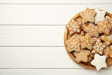 Tasty Christmas cookies with icing on white wooden table, top view. Space for text