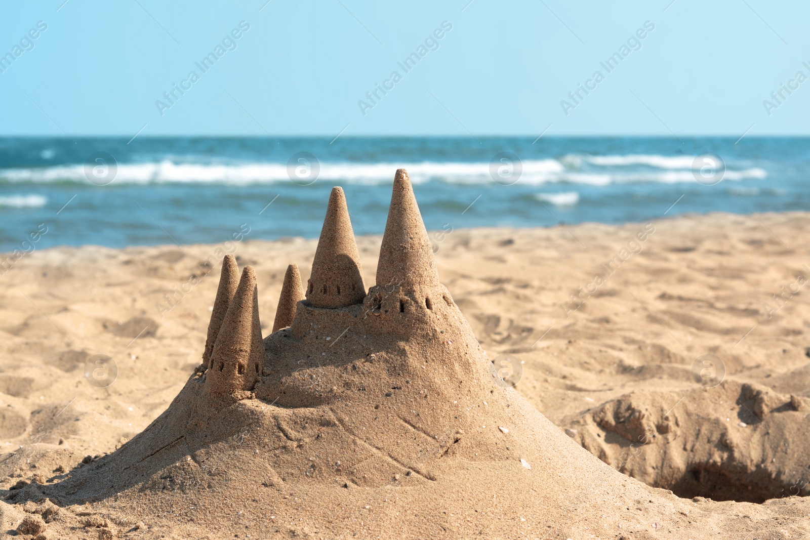 Photo of Beach with sand castle near sea on sunny day