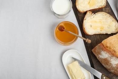 Photo of Sandwiches with butter, honey and milk on white table, flat lay. Space for text