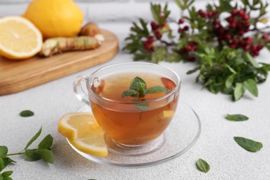 Photo of Glass cup of delicious immunity boosting tea with ingredients on light grey table