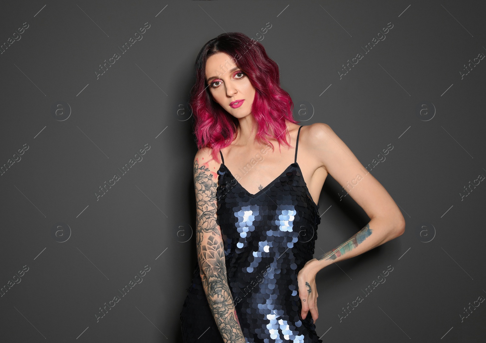 Photo of Beautiful woman with tattoos on arms against black background