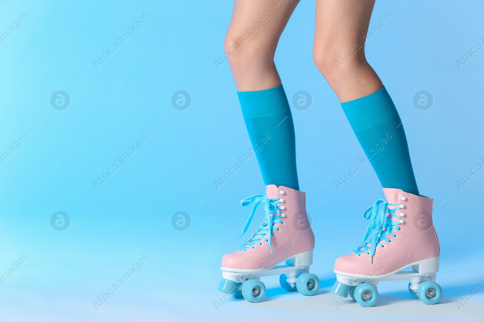 Photo of Woman with vintage roller skates on color background, closeup. Space for text