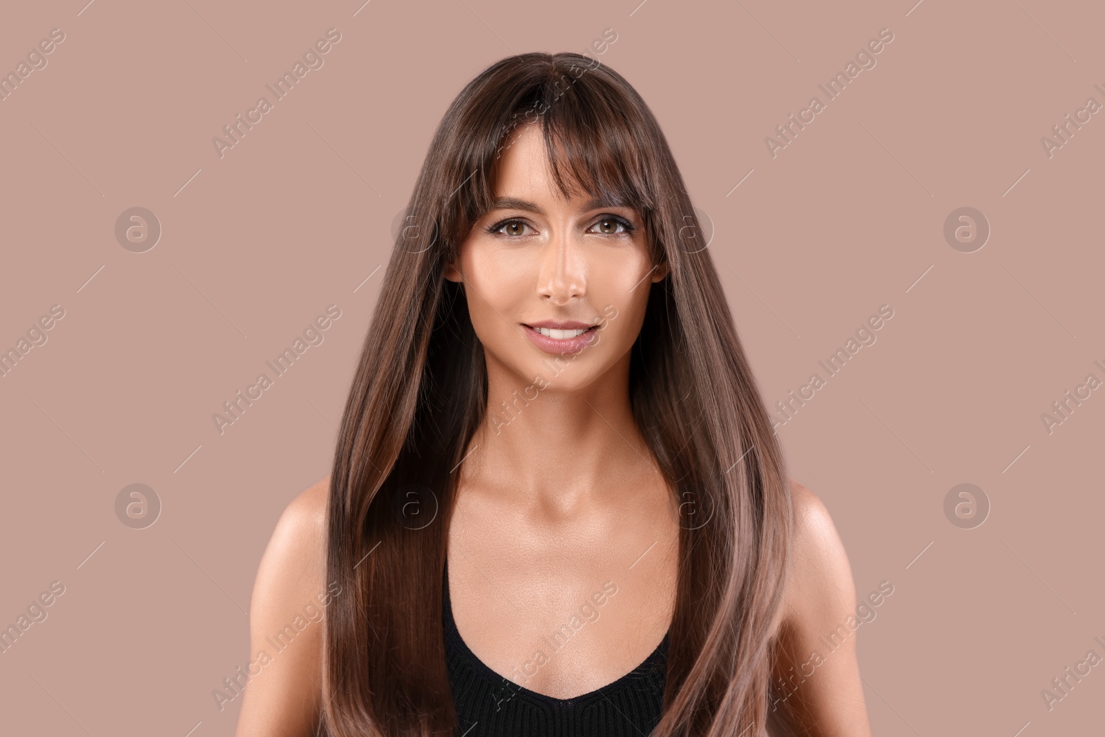 Photo of Hair styling. Portrait of beautiful woman with straight long hair on pale brown background