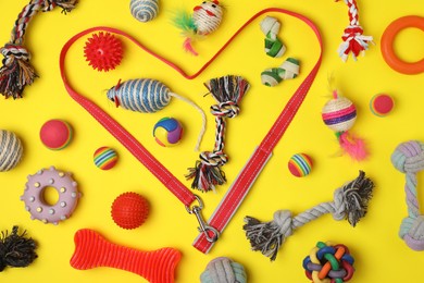 Photo of Flat lay composition with pet leash and toys on yellow background