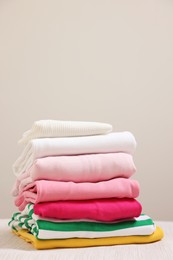 Photo of Stack of folded clothes on wooden table against grey background, space for text