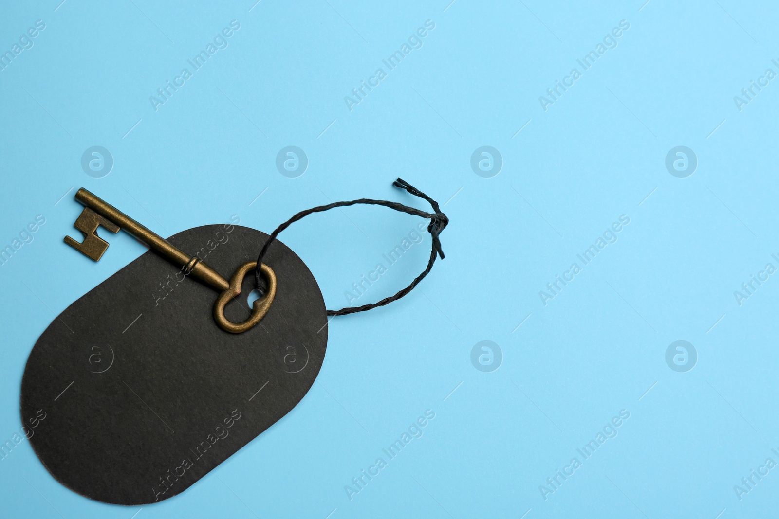 Photo of Vintage key with blank tag on light blue background, top view and space for text. Keyword concept